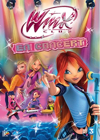 The poster for the 'Winx in concert' DVD. Bloom is in the foreground, positioned on the bottom tight of the DVD, pointing at the viewer and holding a light-blue microphone on a stand. She's wearing a light-blue sleeveless top with a dark blue shirt underneath. Her skirt has a light-blue and dark-blue plaid pattern and a black belt anround her hips with two pink studs and chains hanging off them. Behind her is a crowd of blue human silhouettess and above them are the rest of the Winx fairies. Musa is playing a red and white electric guitar with a black neck. She's wearing a bright-pink jacket with a black horizontal stripe across it. Underneath it, she has a grey top layered over a black one. Her skirt has a bright pink and black plaid pattern, and she's also wearing dark-blue, almost black, leggings. To the right of her is Tecna playing a light-purple keytar. She's wearing a light-purple crop-top layered over a dark-teal shirt. She has one red fingerless glove on her right hand. She's wearing a light-purple skirt. Aisha / Layla is playing the drums to the right of Tecna. She's sitting behind them and is wearing a neon-yellow tank-top with a dark-blue five-pointed star on the chest. Above the three fairies are Stella and Flora, shown from the waist up and enlarged. Stella's back is to Flora and she's looking over her shoulder while playing an orange guitar with a black neck. She's wearing a long-sleeved orange jacket. Flora is to the right of Stella. She's playing a light-pink and white guitar with a hot-pink strap that's on her shoulder. She is wearing a hot-pink jacket with a black sparkly top. Above the girls are multi-coloured spotlights. Their lights are various shades of pink, light-blue, yello, and a bit of green. At the top of the DVD cover is the shiny Winx Club logo in hot-pink with an emboss effect on it. Behind it is a white glow. Underneath it are the words 'EN CONCERT' shown in all caps and a sans-serif font. They have a disco-ball-like texture on them and their colours are a gradient from light-blue to light-yellow going from left to right. They're positioned on a jagged shape with some kind of a hot-pin and light-pink pattern.