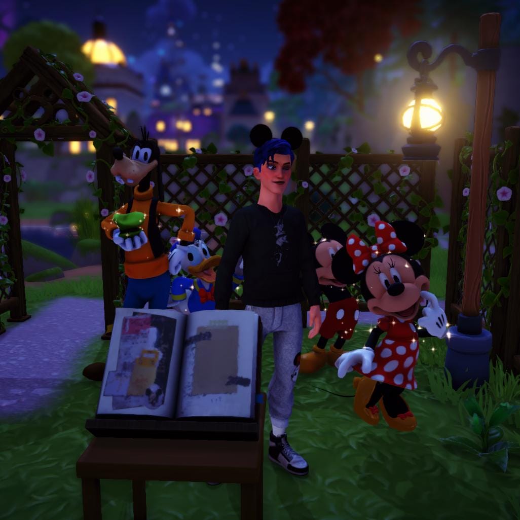Goofy, Donald Duck, the player, Mickey Mouse, and Minnie Mouse posing behind a scrapbook which is propped up on a small table in front of them. They all are happy and celebratory.